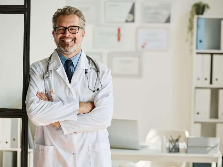 Mature male doctor standing and smiling in a medical office setting